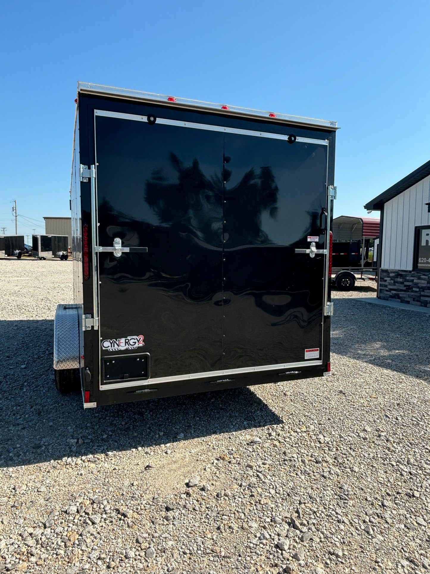Black trailer on a gravel surface with clear blue sky